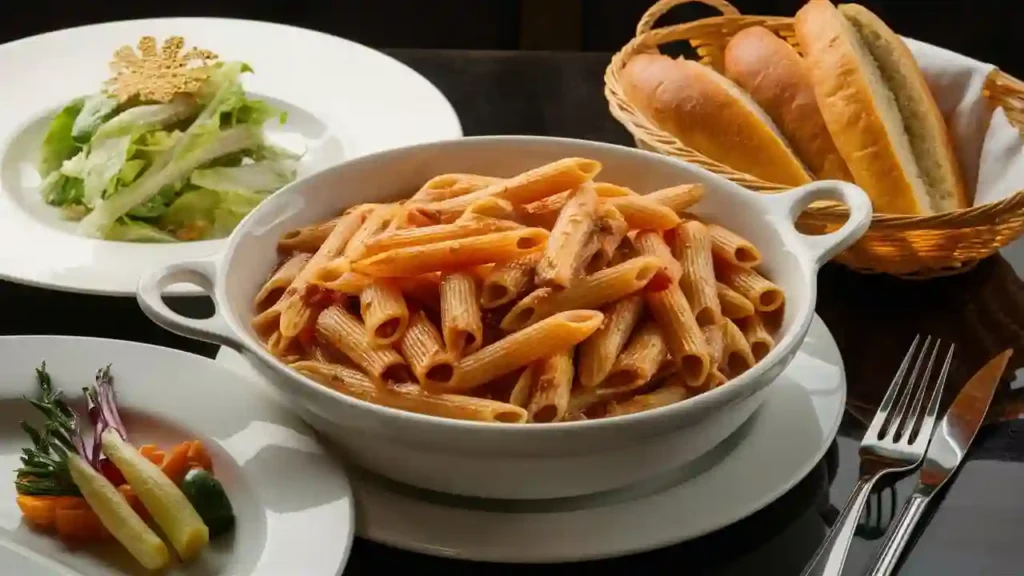 Cooked penne pasta served in a bowl, garnished with fresh herbs and grated cheese