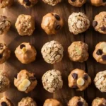 Homemade energy bites on a wooden board, made with oats, nut butter, chia seeds, and chocolate chips.